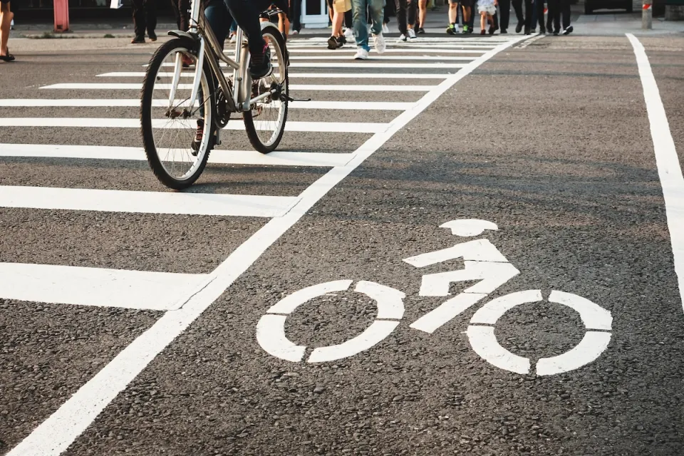 Low angle of pedestrians and a bicycle crossing the street at an urban crosswalk.